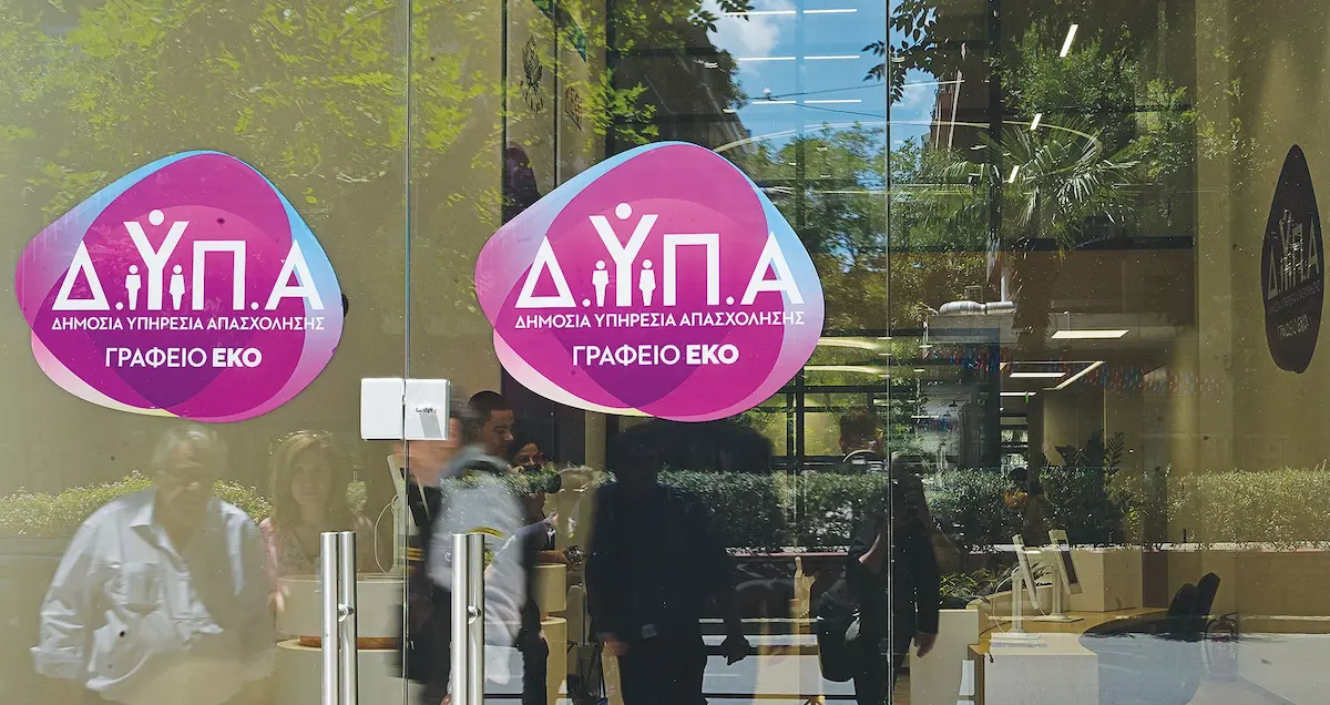 Εξωτερική όψη γραφείου της ΔΥΠΑ με το λογότυπο της Δημόσιας Υπηρεσίας Απασχόλησης στην είσοδο.